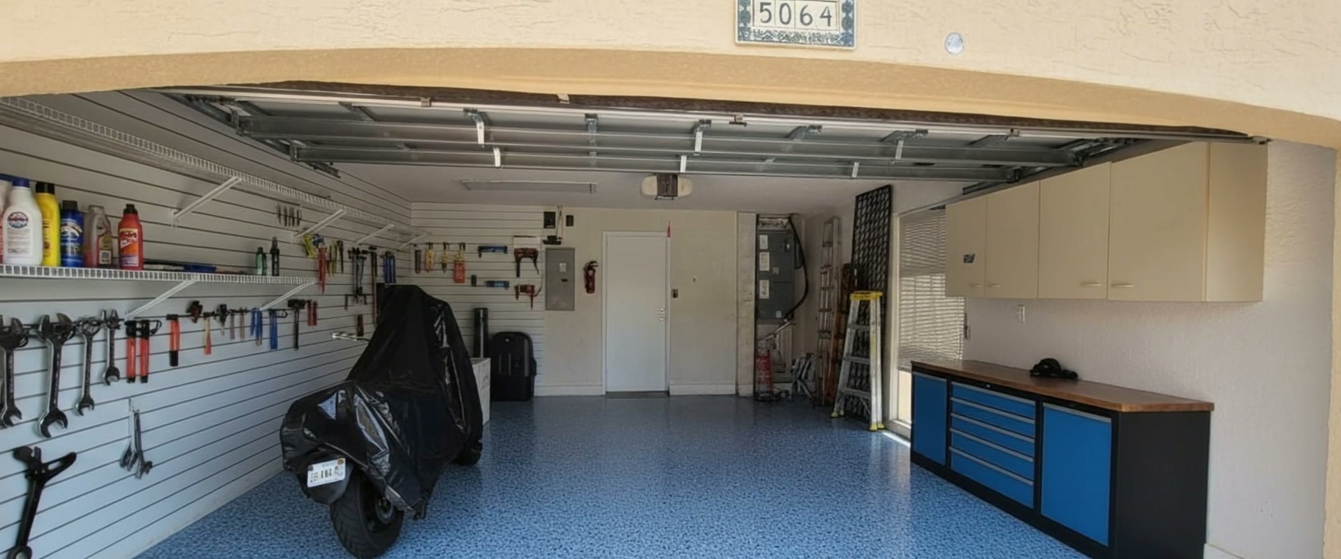 The same garage after a blue flake epoxy floor coating, with a tool wall and finished cabinets.